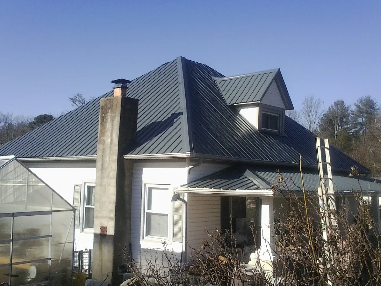 Dark blue standing seam metal roof on a white farmhouse with dormer — Slate & Tile Roof Repair by Roofing Brothers in Corryton