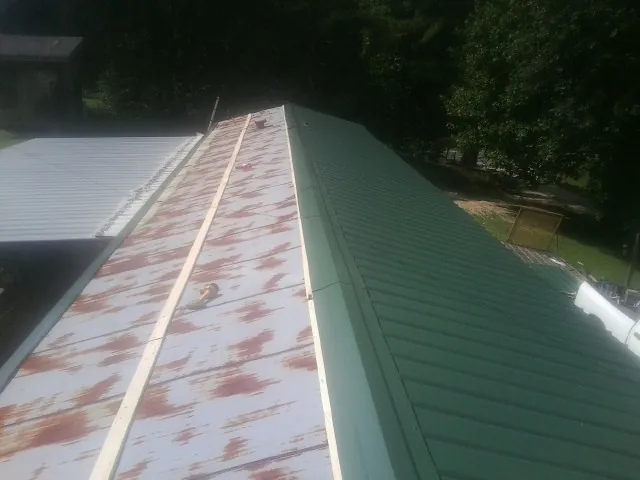 Old rusted panels beside newly installed green metal roofing — Wind Damage Roof Repair by Roofing Brothers in Corryton