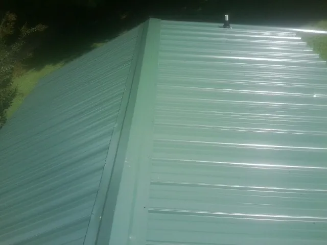 New green metal panels meeting at the ridge of a roof — Flat Roof Repair work by our crew in Corryton