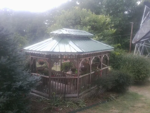 Green metal roof on a backyard gazebo surrounded by garden beds in Corryton