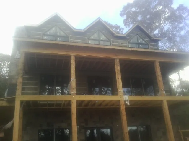 Dormers and porch framing on a large log home under construction — Roof Coating work by our crew in Corryton