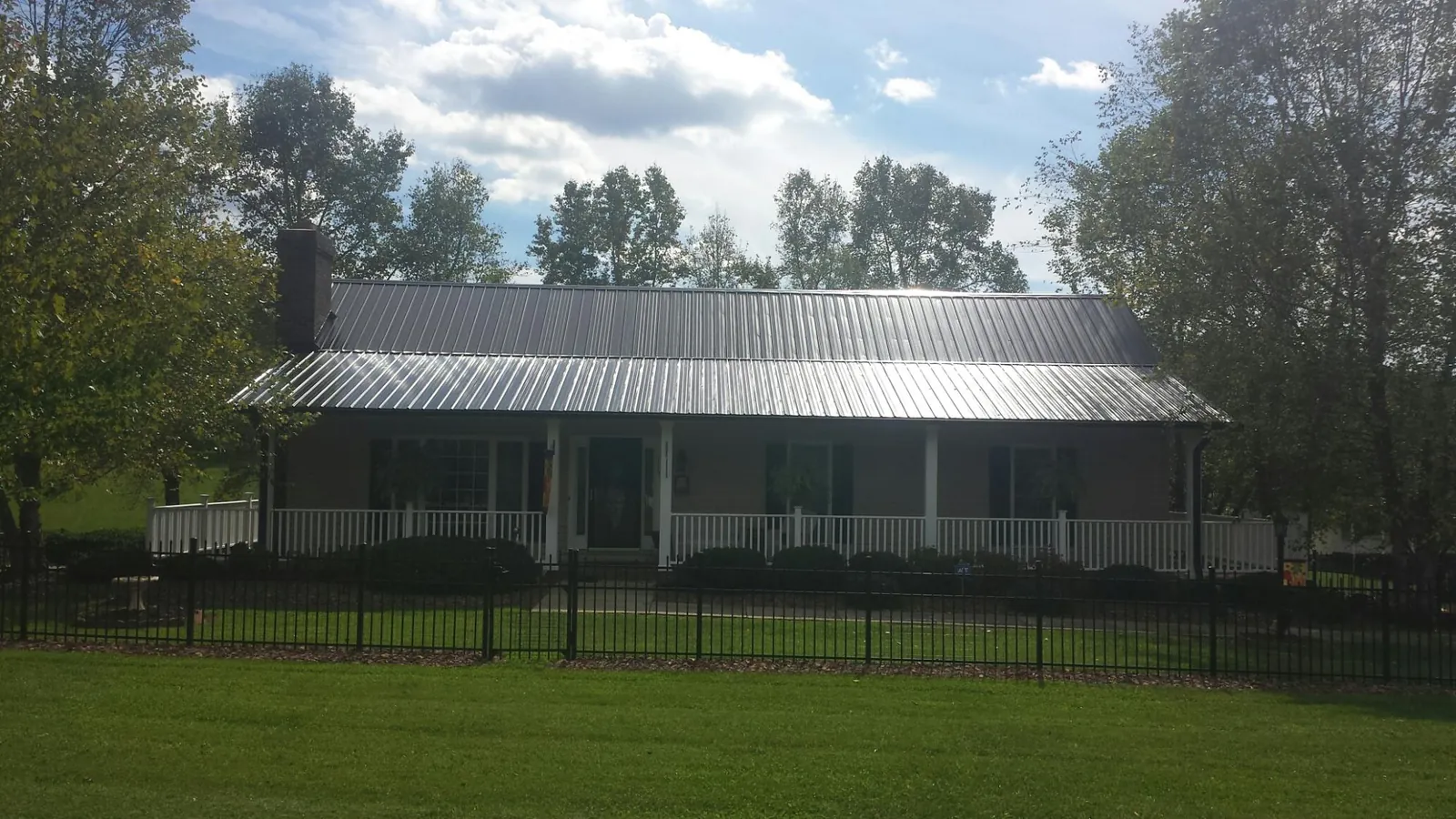 Gray metal roof on a brick ranch with a full width front porch — Gutter Guard Installation work by our crew in Corryton