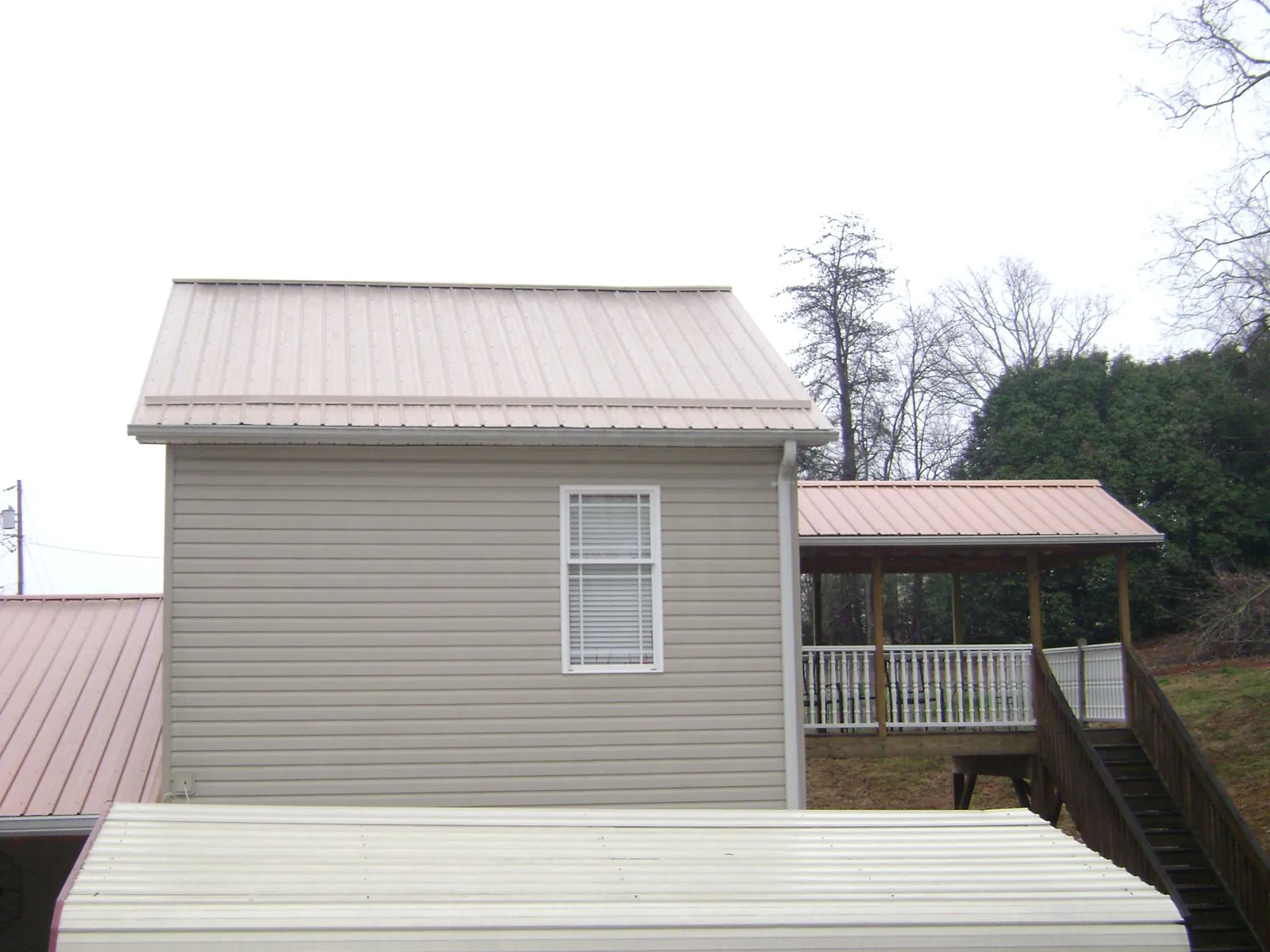 Tan metal roofs on a two story addition and attached porch, from a Roof Replacement job in Corryton