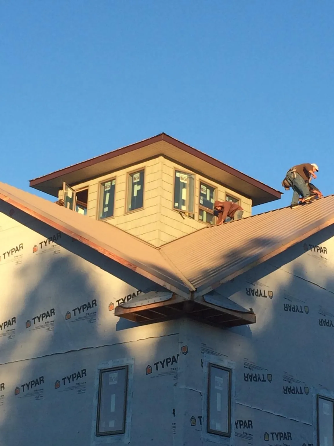 Roofers working around a rooftop cupola on a new metal roof at sunset — Roof Waterproofing in Corryton by Roofing Brothers